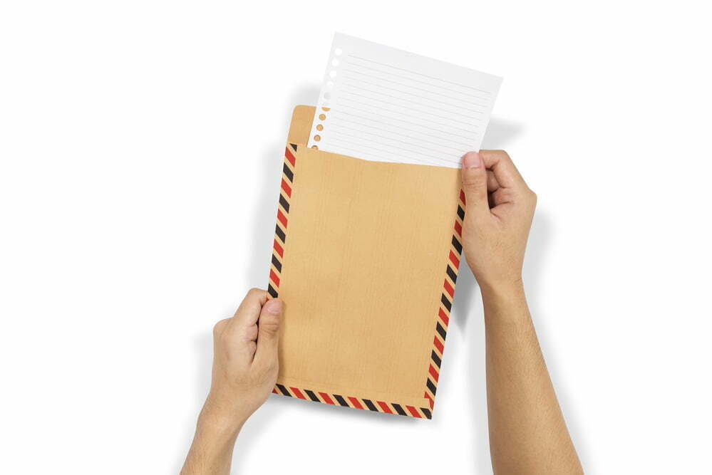 Hands insert the paper into brown envelope